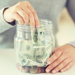 woman putting money in a glass jar