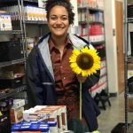 woman holding a sunflower in pantry behind donations